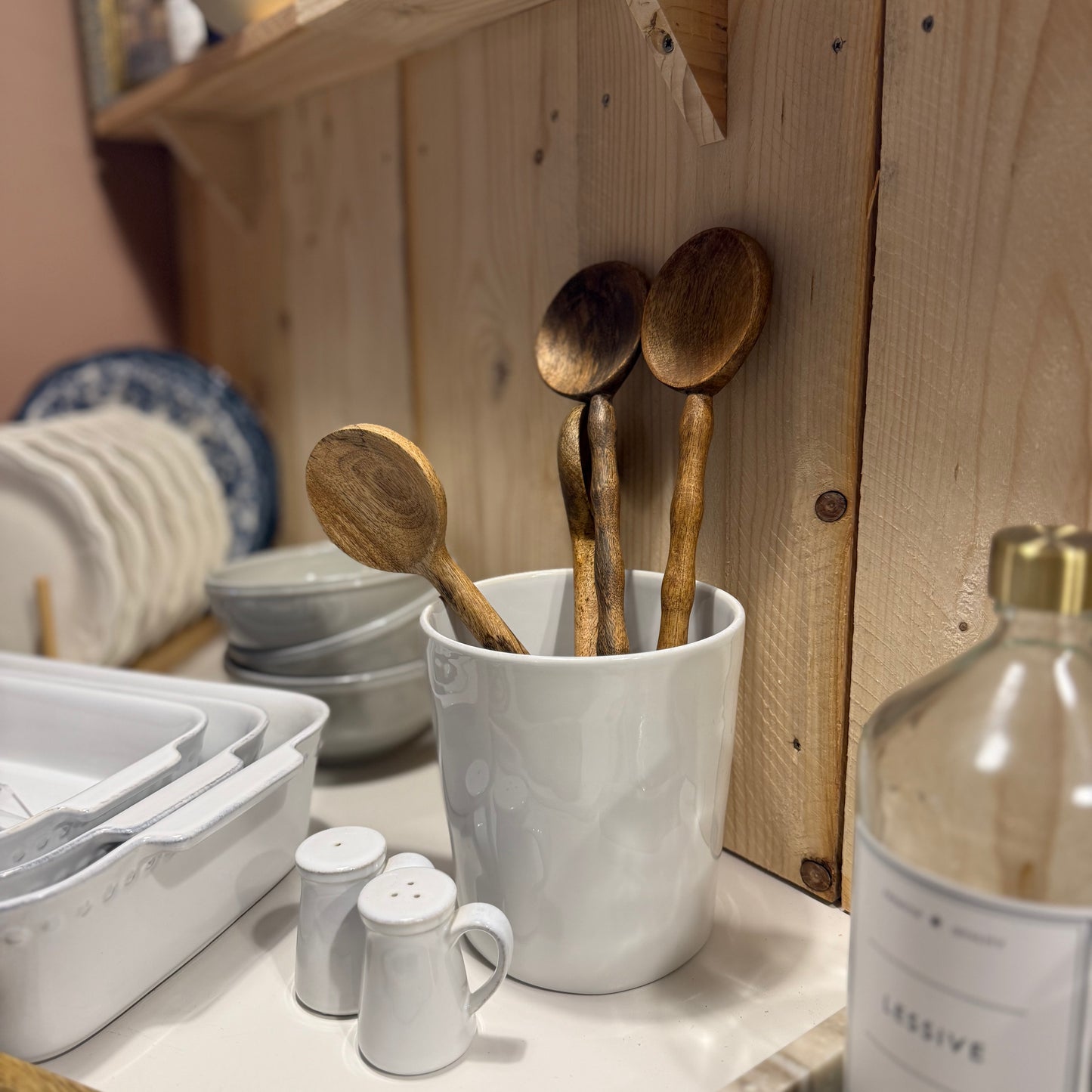 Pot en grés blanc brillant, pour ustensiles de cuisine. Posé sur un plan de travail de cuisine style campagne chic. Crédence en bois. Charme de l’ancien