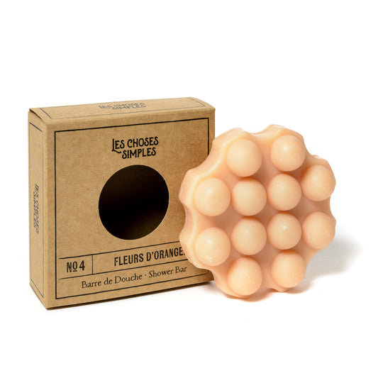 Shower Bar Les Choses Simples, savon solide hydratant à la fleur d'oranger, pour la douche, posé près de son emballage en carton