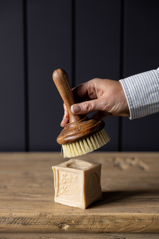 Petite brosse en bois posée sur un plan de travail, style maison chaleureuse.