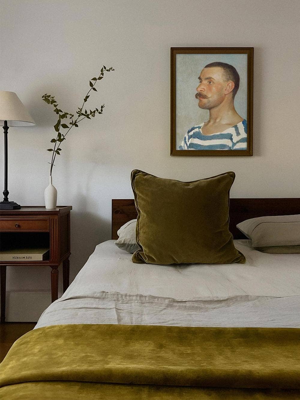 Reproduction Le gondolier accroché au dessus d'un lit avec coussin en velours vert, décoration murale élégante inspirée des marins.