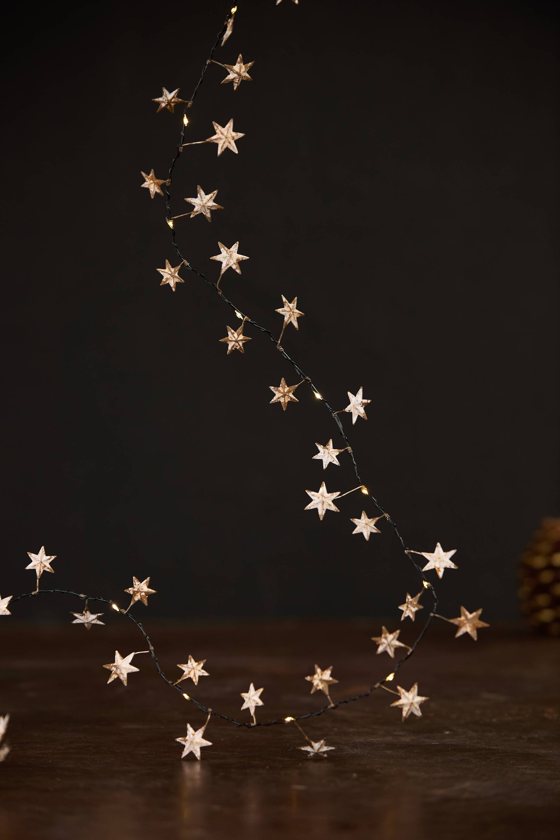 Guirlande lumineuse en métal doré avec étoiles et LED blanc chaud pour décoration de Noël.
