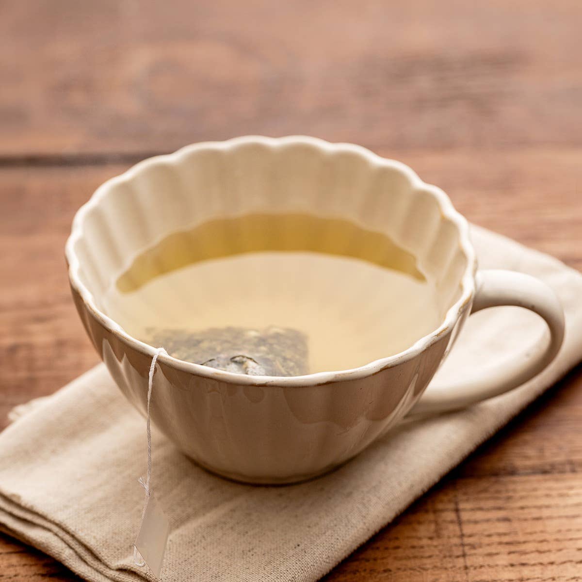 Mug MELIDA en grès crème de 30 cl, inspiré d’une tasse à thé avec surface cannelée, bord ondulé et anse arrondie.