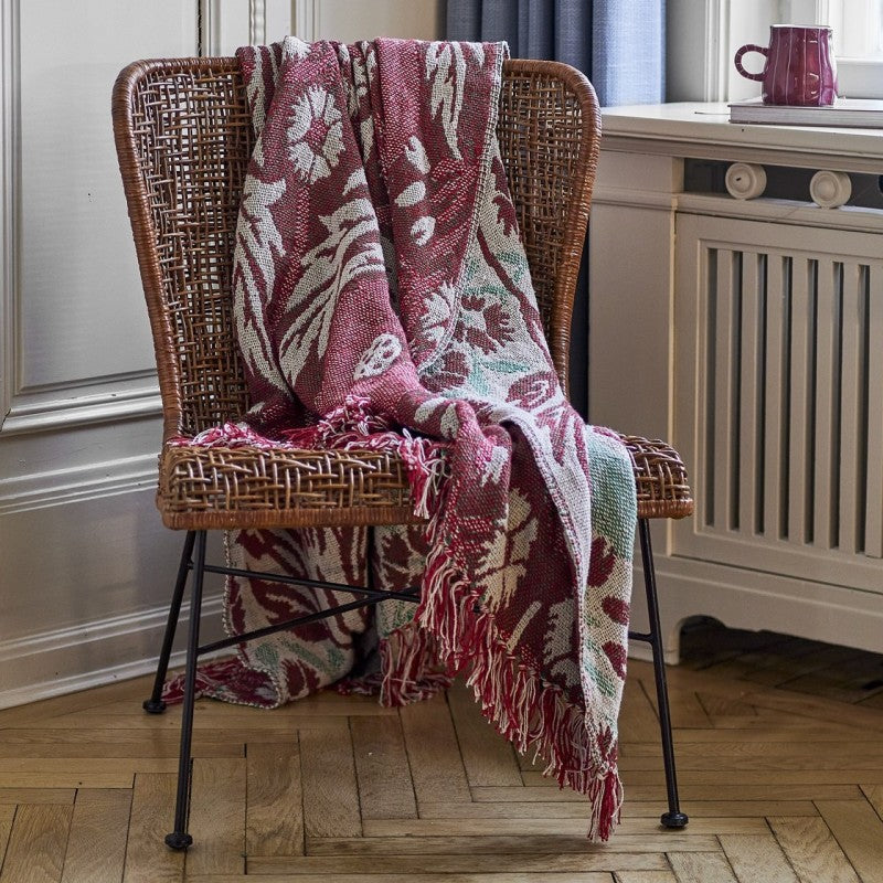 plaid posé sur une chaise en rotin dans une chambre