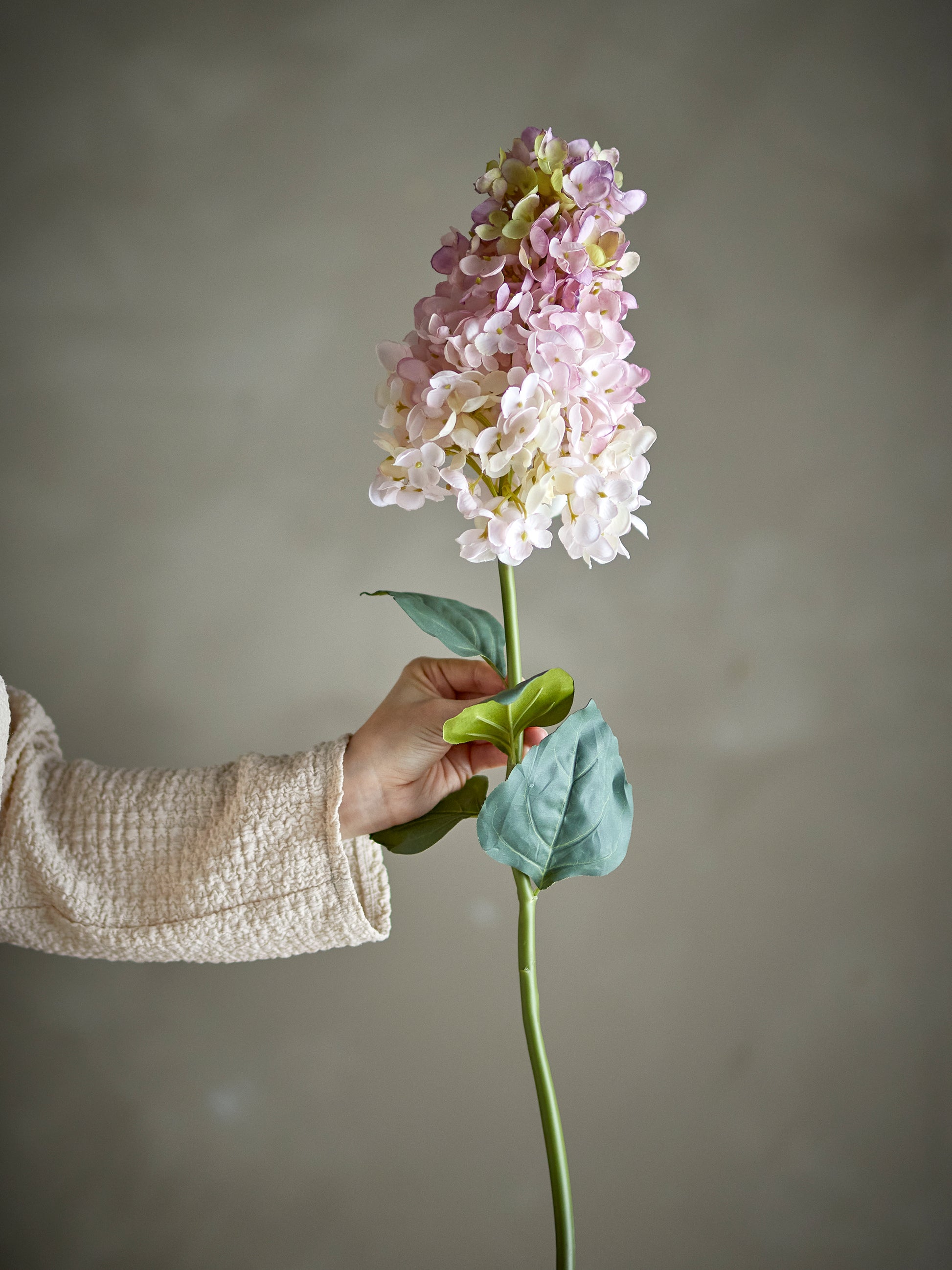 Tige d’hortensia artificielle rose et blanche tenue à la main, fleur décorative élégante pour vase.